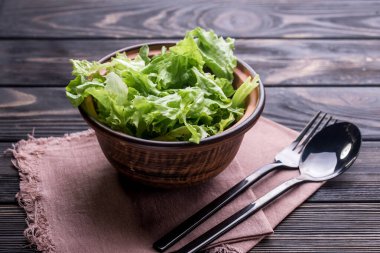 Marul ve zeytinyağlı taze salata derin bir pialada, çatal bıçaklı yemek masasında..