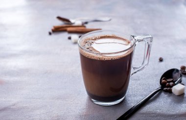 Lezzetli ve mis kokulu kahve, bir bardak süt, kokulu tarçın çubukları, kahve çekirdekleri, şeker küpleri, masada.