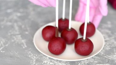 Pembe eldivenli bir pasta şefi kırmızı kadife bir tatlı hazırlar. Çubukta kek. Kek patlakları