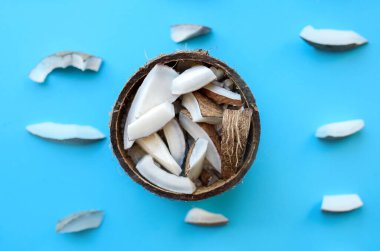 Taze hindistan cevizi mavi arka planda, küçük akosoz parçalarıyla birlikte duruyor. Hindistan cevizi talaşı. Yukarıdan görüntüle.