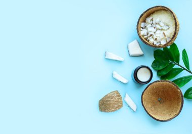 Hindistan cevizi parçaları, hindistan cevizi kırıntıları, yeşil yapraklar, mavi arka planda Shea yağı. Mesajlaşmak için bir yer. Yukarıdan görüntüle