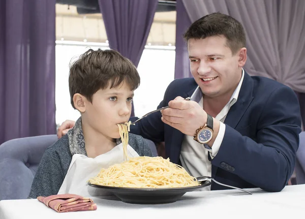 Papa füttert seinen Sohn mit Spaghetti — Stockfoto