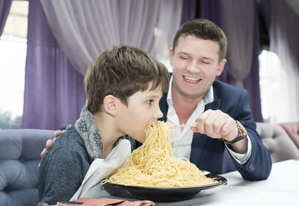 Папа кормит своего сына спагетти — стоковое фото