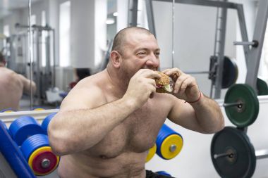  Aç adam bir hamburger et ve peynir jimnastik salonu ile çiğneme