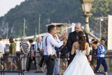 Düğün fotoğrafçıları Budapeşte sokaklarında bir grup yeni evli bir çift için bir fotoğraf oturumu düzenliyor.