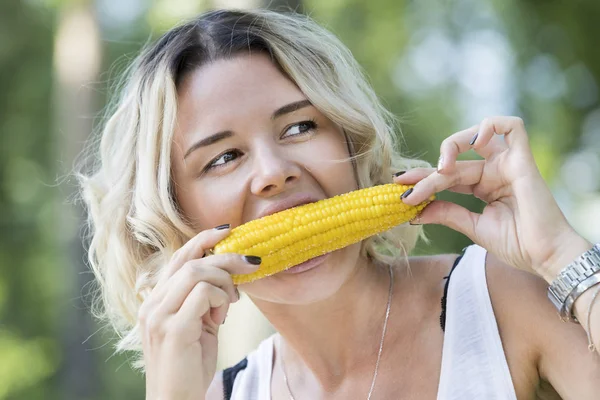 The girl is eating boiled sweet corn — Stock Photo, Image