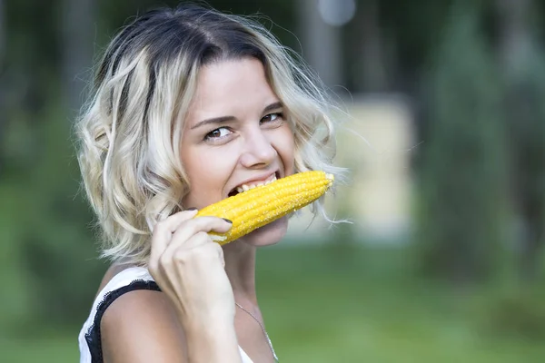The girl is eating boiled sweet corn — Stock Photo, Image