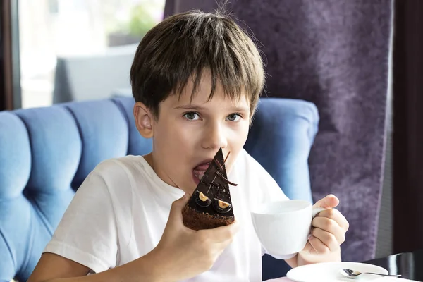 El chico se está comiendo un pedazo grande de pastel. —  Fotos de Stock