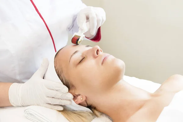 Mulher sofre o procedimento de terapia de micro agulha médica com um moderno instrumento médico derma rolo . — Fotografia de Stock