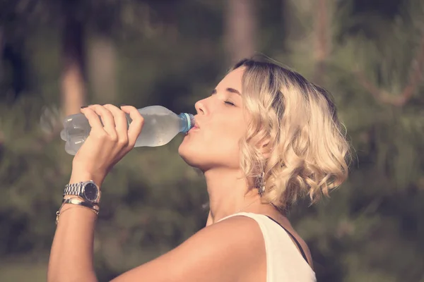 Girl drinks water in a summer park — Stock Photo, Image