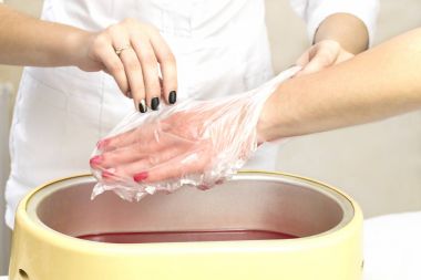 Güzellik salonunda kadın ellerine parafin tedavisi uygula 