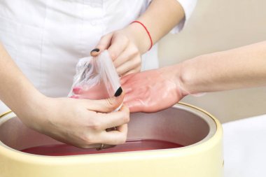 Güzellik salonunda kadın ellerine parafin tedavisi uygula 