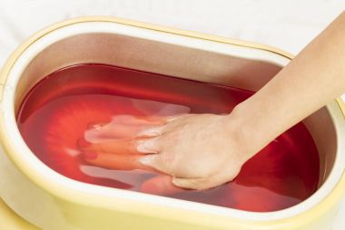 Güzellik salonunda kadın ellerine parafin tedavisi uygula