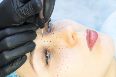 Permanent microblasting tattooing freckles to a woman in a beauty salon clipart