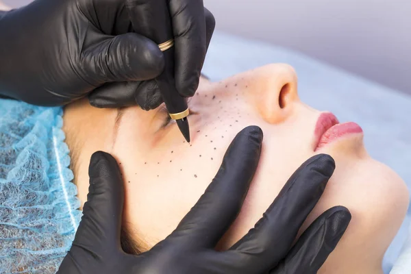 Permanent microblading tattooing freckles to a woman in a beauty salon