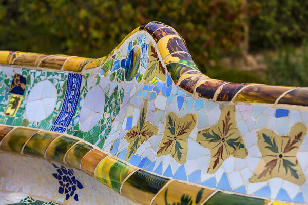 BARCELONA, SPAIN - 13 JANUARY 2018: Elements of mosaic fragments Gaudi's mosaic work in Park Guell In winter in the city of Barcelona.