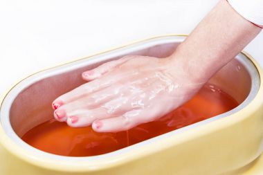 Güzellik salonunda kadın ellerine parafin tedavisi uygula