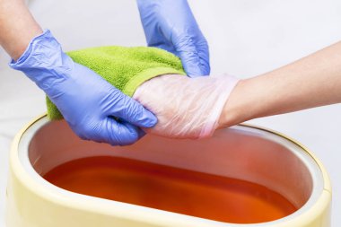 Güzellik salonunda kadın ellerine parafin tedavisi uygula