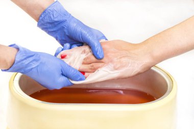 Güzellik salonunda kadın ellerine parafin tedavisi uygula