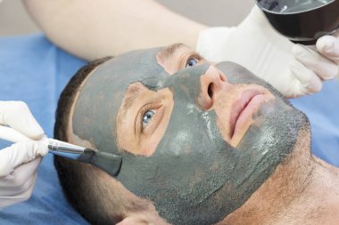 Bir adam yüzünü Güzellik Salonu bir kil maskesi ile temizlik işlemi yapar