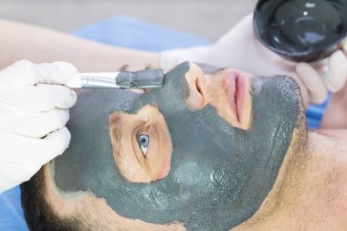Bir adam yüzünü Güzellik Salonu bir kil maskesi ile temizlik işlemi yapar