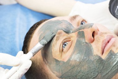 Bir adam yüzünü Güzellik Salonu bir kil maskesi ile temizlik işlemi yapar