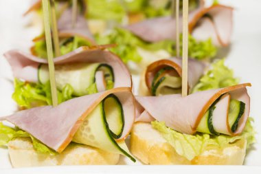 Çelik şölen raflarında et, sebze ve balık bulunan minyatür kanepeler..