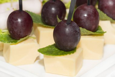 Çelik şölen raflarında et, sebze ve balık bulunan minyatür kanepeler..