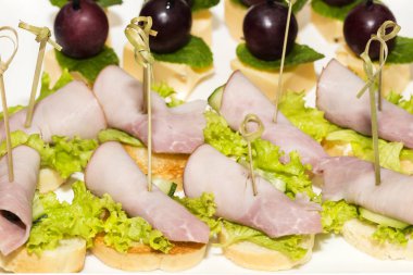 Çelik şölen raflarında et, sebze ve balık bulunan minyatür kanepeler..