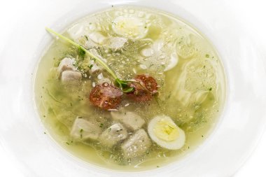 Bir restoranın beyaz arka planında bıldırcın yumurtasıyla süslenmiş kümes hayvanları çorbası..