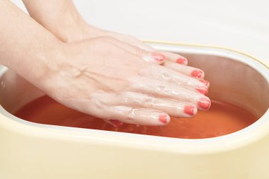 Güzellik salonunda kadın ellerine parafin tedavisi uygula 