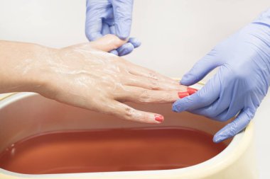 Güzellik salonunda kadın ellerine parafin tedavisi uygula 