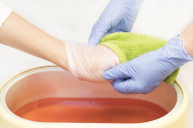 Güzellik salonunda kadın ellerine parafin tedavisi uygula 