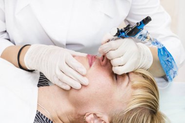 Dudak dövmesi ve güzellik salonundaki orta yaşlı kadın şeklinin düzeltilmesi..