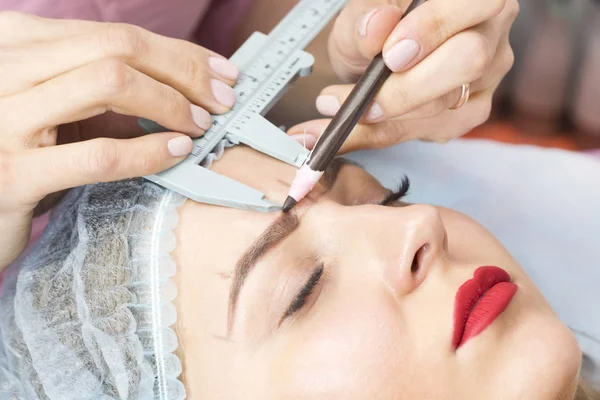 Microblading eyebrow tattoo procedure in a beauty salon for women.
