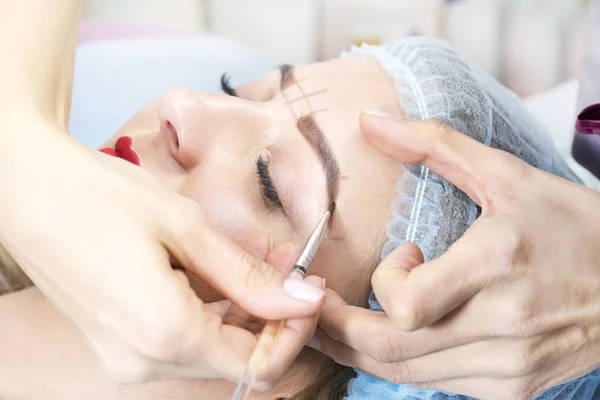 Microblading eyebrow tattoo procedure in a beauty salon for women.