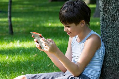 Parkta doğayla ilgili elektronik cihaz tableti olan çocuk..