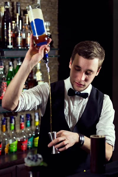 バーの後ろでバーテンダーとして働いてる若い男が客のために酒を用意してる — ストック写真