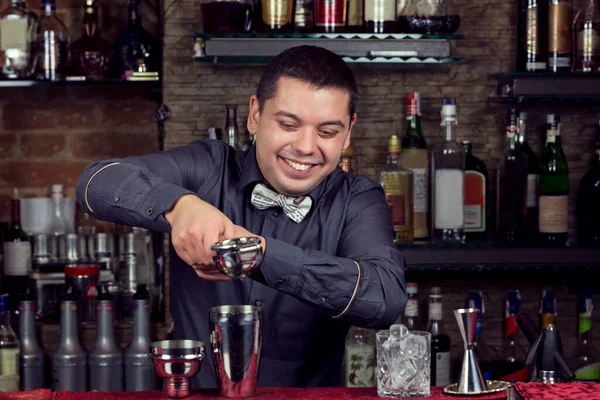 バーの後ろでバーテンダーとして働いてる若い男が客のために酒を用意してる — ストック写真
