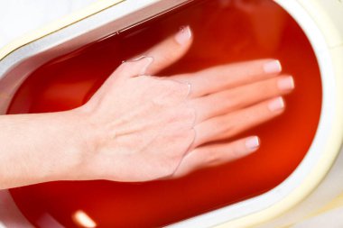 Kadın elinin parafin terapisi bir güzellik salonunda çekilir..