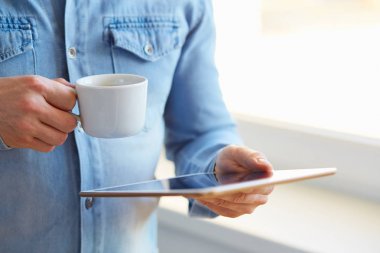 Tablet ve kahve tutan adam