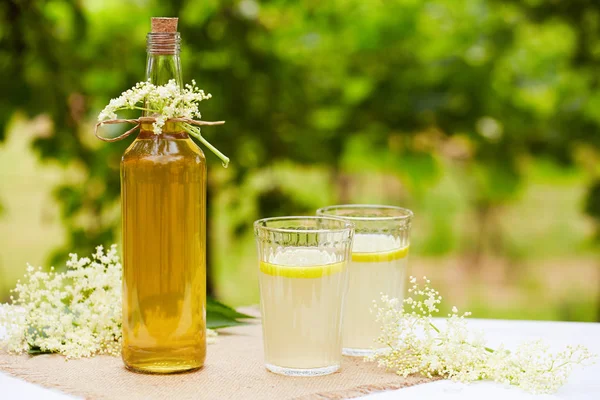 Homemade elderflower syrup in a bottle with elderflowers