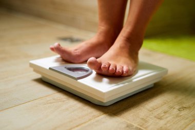 Kadın banyoda ağırlık tartısında duruyor.