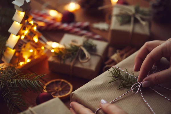 Woman wrapping Christmas gift in paper on table