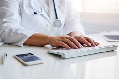 Tıp ofisinde bilgisayarla çalışan kadın doktor.