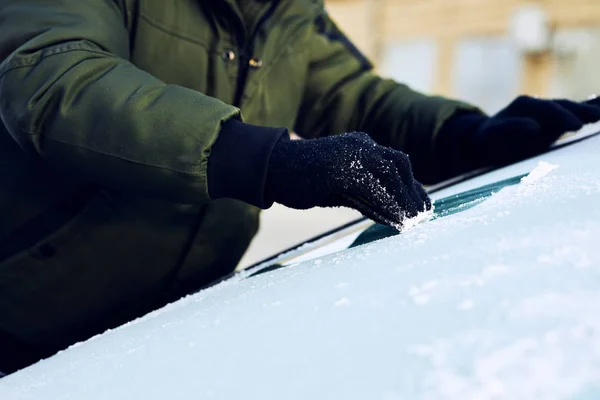 車のフロント ガラスの氷をこする男のクローズ アップ — ストック写真