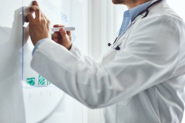 Erkek doktor beyaz tahtadaki hastaların istatistiklerini çizdi