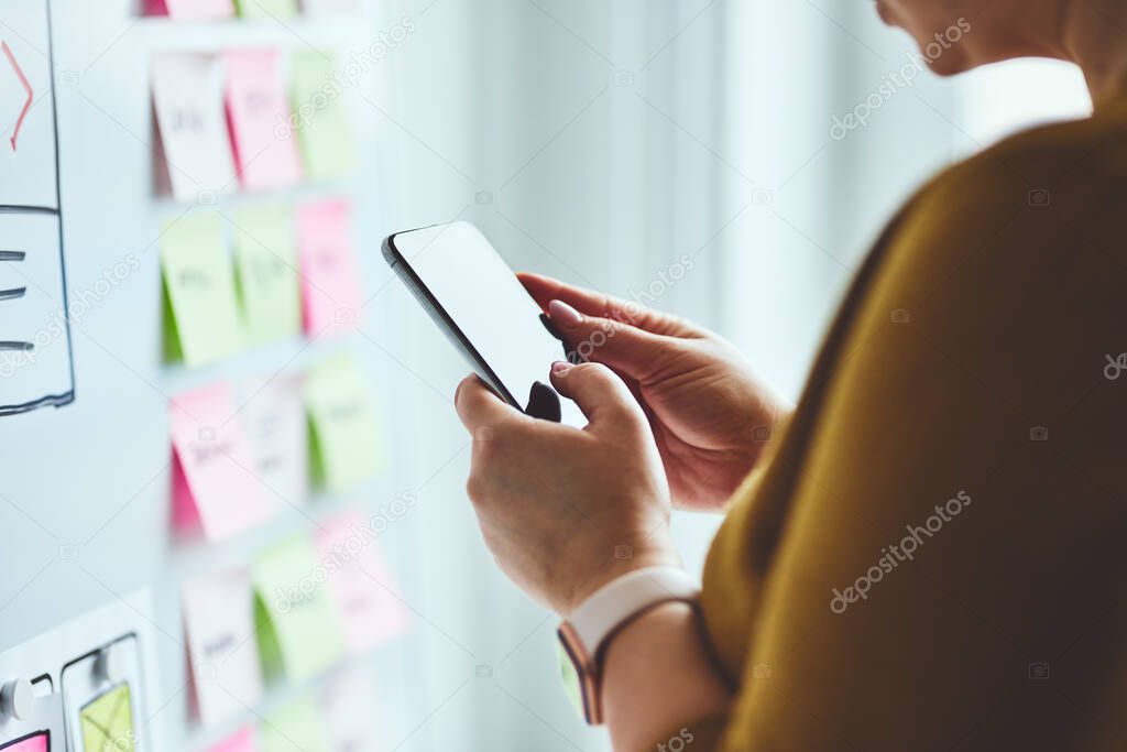Woman with mobile phone planning website on whiteboard