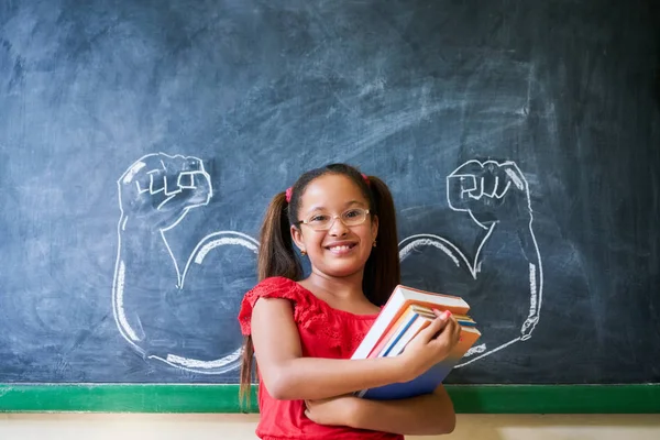 Hispanisches Mädchen hält Bücher im Klassenzimmer und lächelt — Stockfoto