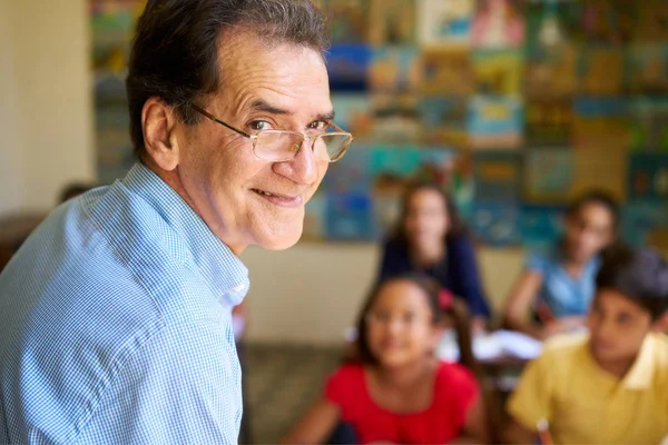 Przyjazny dla nauczyciela w klasie szczęśliwy profesor uśmiecha się do kamery — Zdjęcie stockowe